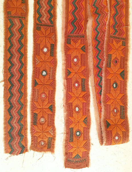 A hand embroidered strip with mirrors of sandstone red coloured cotton.