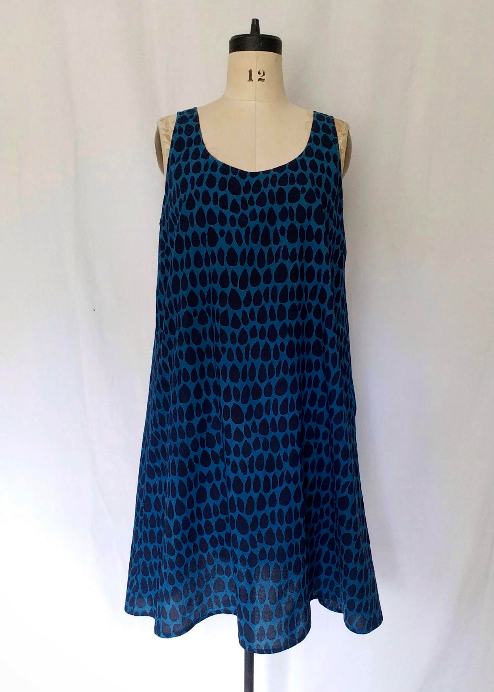 Mannequin wearing Gigi dress in butti print. 1-2 inch thick straps and sits near the knees.