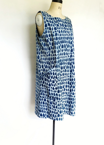Mannequin wearing sleeveless pocket jumper with pockets in indigo and white butti print.