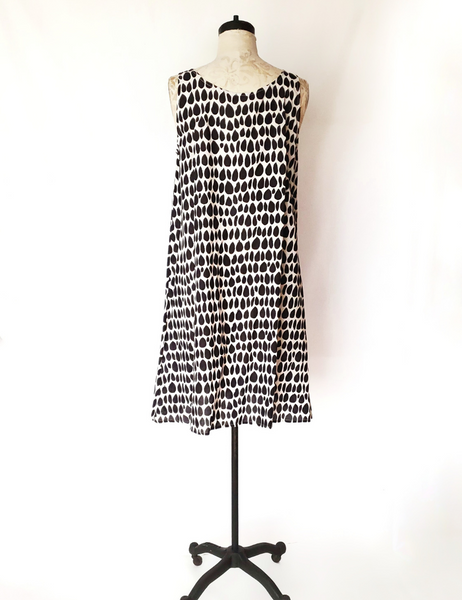Mannequin wearing Gigi dress in butti print. 1-2 inch thick straps and sits near the knees.