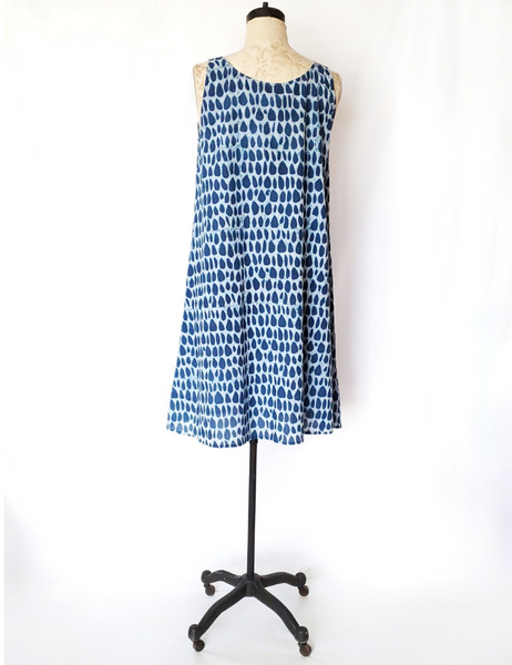 Mannequin wearing Gigi dress in butti print. 1-2 inch thick straps and sits near the knees.