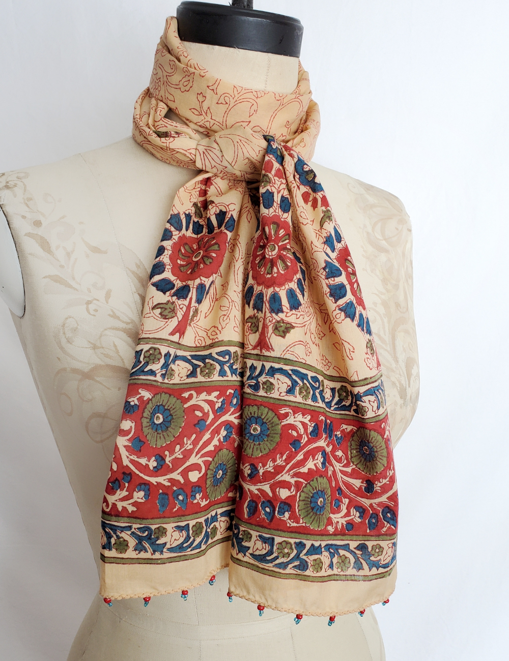 Long scarf tied around mannequins neck. Red, blue and green details.